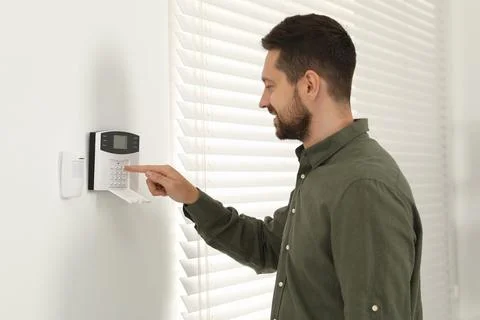 Man entering code on home security system indoors Stock Photos