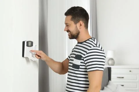 Man entering code on home security system indoors Stock Photos