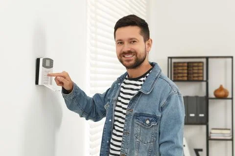 Man entering code on home security system indoors Stock Photos