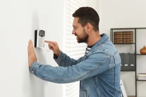 Man entering code on home security system indoors Stock Photos