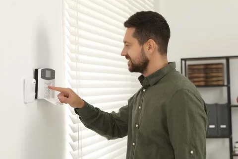 Man entering code on home security system indoors Stock Photos