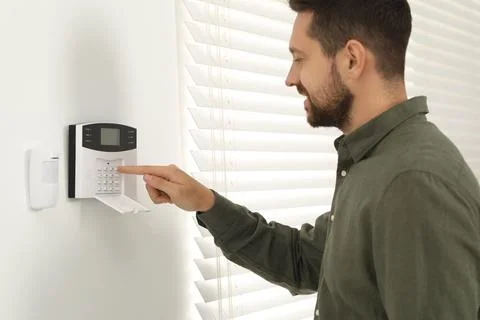 Man entering code on home security system indoors Stock Photos