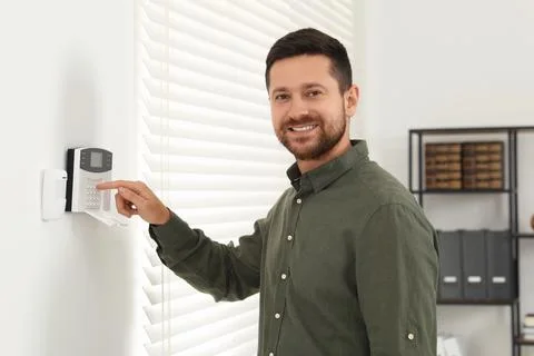 Man entering code on home security system indoors Stock Photos