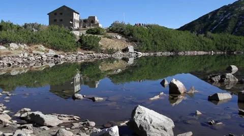 Man entering hut at the edge of mountain lake Stock Footage 40254630