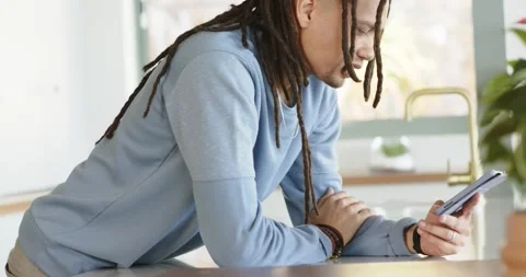 Man entering kitchen and leaning on counter while tapping and scrolling tablet Stock Footage 342927160