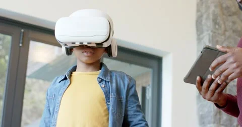 Man entering living room with tablet and positioning VR headset on child while Stock Footage 344325532