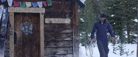 Man entering a log cabin with his husky dog Stock Footage 68496552