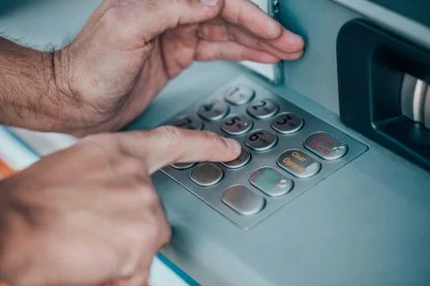 Man entering a PIN code for his credit card at an ATM, withdrawing money Stock Photos