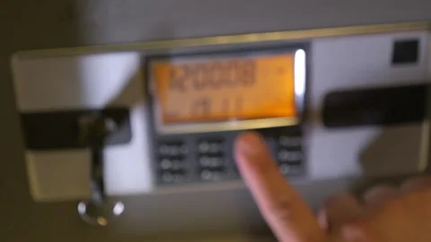 A man enters the correct code into the keypad of a safe Видео 277592912