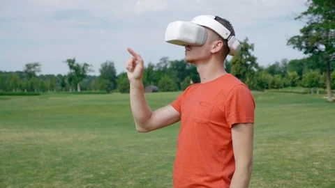 A man enters the frame, puts a VR headset on his head in a park Stock Footage 112805407