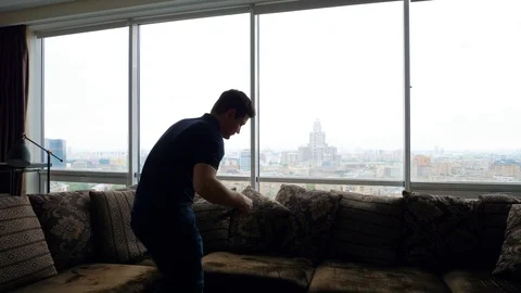Man enters the frame. Takes a tablet, sits on a sofa Stock Footage 103199505