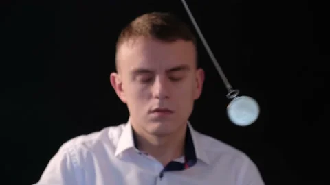 A man enters hypnosis while watching a swinging pendulum Stock Footage