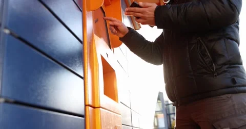 Man enters parcel code on screen and picks up parcel from post office slow Stock Footage 257666196