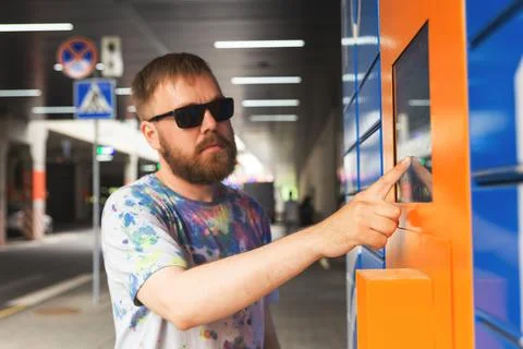 Man enters parcel code on screen and picks up parcel from automated postal ma Foto stock