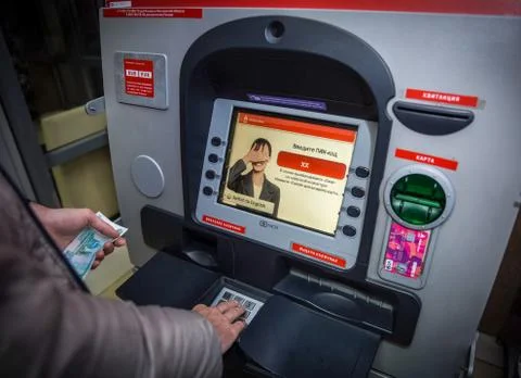 A man enters a PIN code in an ATM of Alfa Bank. Stock Photos