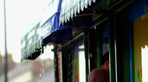 Man enters shop during heavy rain Stock Footage 44019388