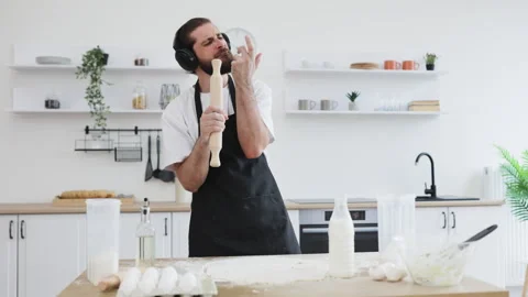 Man entertainingly cooking while listening to music in a modern kitchen Stock Footage 306479233