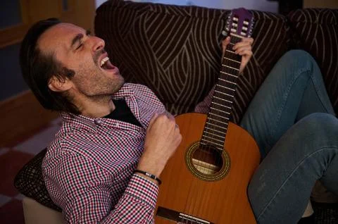 Man Enthusiastically Singing While Playing an Acoustic Guitar Indoors Stock Photos
