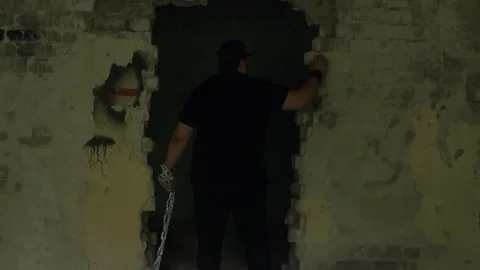 Man escaping prison breaking through wall with chains Stock Footage 301328217