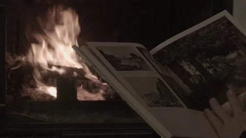 A man in the evening examines a book in front of a fireplace Stock Footage 74243889