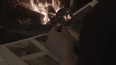 A man in the evening examines a book in front of a fireplace Stock Footage 74244748