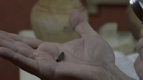 A man examines an antique tip from an arrow Stock Footage 74340464