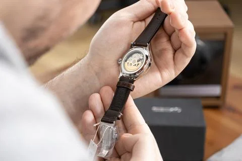 A man examines an automatic mechanical watch with a transparent case back, Stock Photos