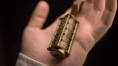 A man examines copper cryptex with numbers,then squeezes cryptex in his hand. Stock Footage 105861152