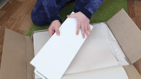 A man examines the elements of a computer desk before assembling. Picks up .. Stock Footage 236689165