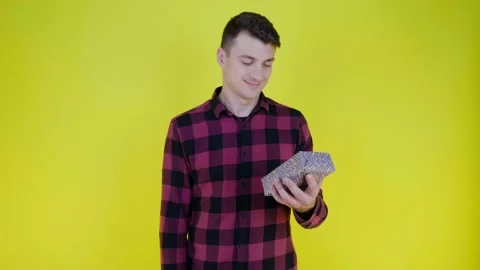 Man examines gift box in hand, rejoices and hugs on chest on yellow background Video stock 136660588