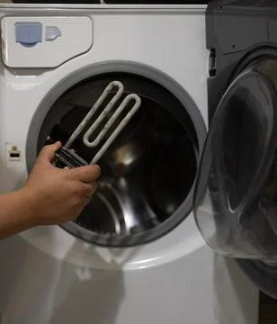 A man examines a heating element with scale against the background of a washing Stock Photos