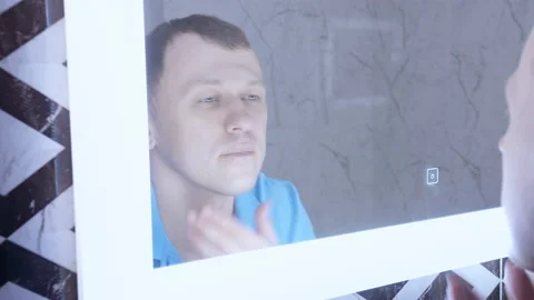 Man examines his reflection in the mirror with the light on Stock Footage 155130630