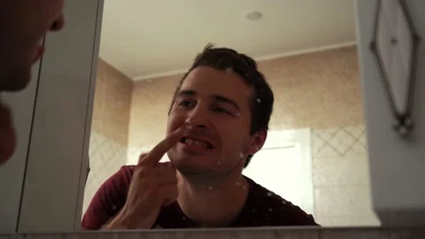 Man examines his teeth through a dirty mirror Stock Footage 161826196