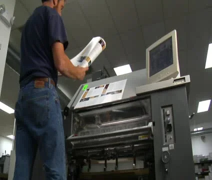 Man examines newly printed material from printing press Video stock 21596332