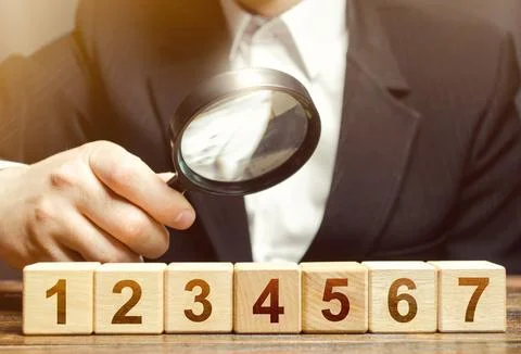 Man examines the numbered blocks with a magnifying glass. Study business pl.. 스톡 사진