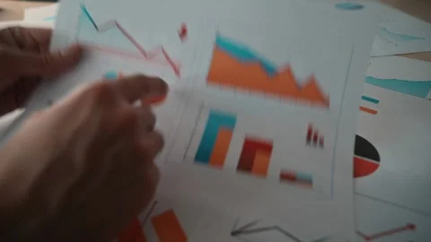 A man examines various charts and graphs spread out on a table, noting important Stock Footage 338302579