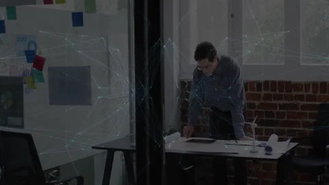 Man examining blueprints, turbine model on desk in tech office, interacting with Stock Footage 308603884
