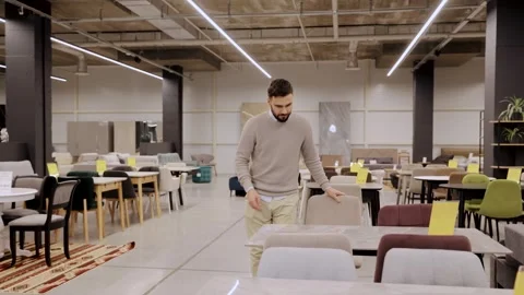 Man examining a chair and table set in a large furniture store, home interior Stock Footage 334654245