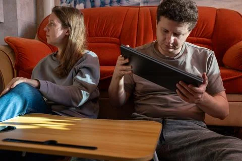Man examining closed laptop while woman sits nearby. Technician cleaning Stock Photos