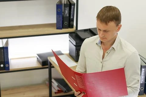 Man examining documents in red folder at office desk Stockfoto's