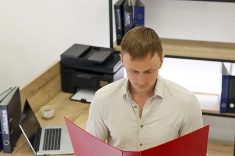 Man examining documents in red office folder Stock Photos