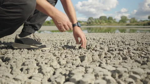 Man Examining Dried Lake Silt After Extreme Heat Stock Footage 344890865