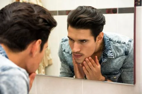 Man examining face in reflection of mirror Stock Photos