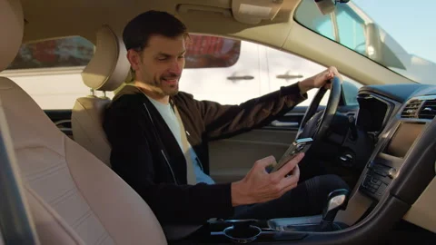 Man examining interior of car before test drive, holding smartphone, showcasing Stock Footage 317701977