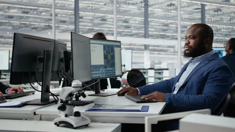 Man examining microchip circuit layouts on computer monitor in factory RD office Stock Footage 335877747