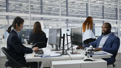 Man examining microchip circuit layouts on computer monitor in factory RD office Stock Photos