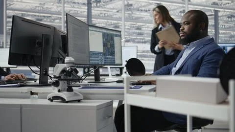 Man examining microchip circuit layouts on computer monitor in factory RD office Stock Photos