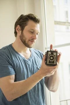 Man examining pinhole camera at window, Munich, Bavaria, Germany Stock Photos