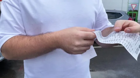 A man examining the receipt,taking note of every expense he made during his.. Stock Footage 249875136