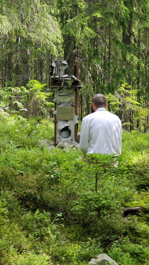 Man examining rusted plane crash wreckage on mountain forest slope Video stock 344877237